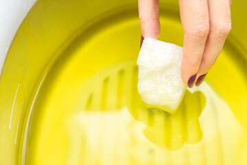 Manicurist melts paraffin in a paraffin bath. wax machine for paraffin therapy. spa manicure procedure. hand and foot spa. wax bath. body wax. hand holding a piece of paraffin. 