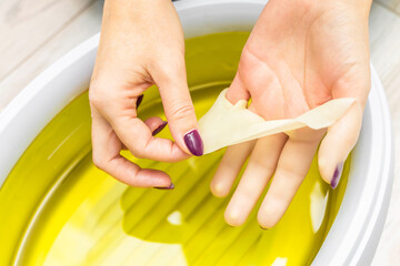 woman doing paraffin therapy for hands, close-up. woman removes hardened paraffin from her hand....