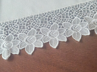 Delicate lace trim featuring intricate floral patterns on a wooden surface