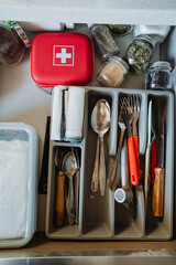 This drawer in the kitchen is meticulously organized to hold cutlery, spices, and a first aid kit,...