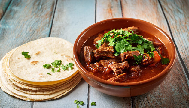 beef birria in a bowl with tortillas stacked on the side and a sprinkle of cilantro on top beaf birria tortillas cilantro homestyle cooking