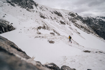 Alpine mountain athlete running and climbing in snow covered winter mountain alpine landscape. Extreme outdoor activities in Hochschwab mountain range, Austria.