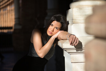 Portrait of young, beautiful, brunette woman, wearing a fancy black dress, looking at the camera,...
