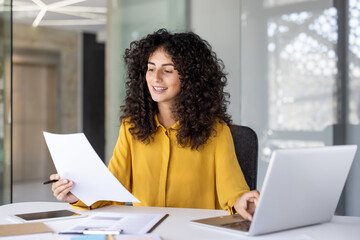 Successful and joyful woman at workplace checking financial reports and contracts. Businesswoman...