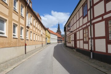 Hinter den Häusern dieser kurvigen Altstadtstraße in Ystad in Südschweden ist der Turm der St.-Maria-Kirche zu sehen.  Es ist ein sonniger Sommertag.
