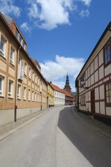 Hinter den Häusern dieser kurvigen Altstadtstraße in Ystad in Südschweden ist der Turm der St.-Maria-Kirche zu sehen.  Es ist ein sonniger Sommertag.