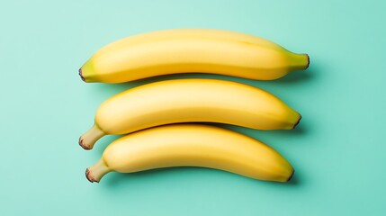 Three yellow bananas laid on a light blue surface, isolated for food, diet, healthy eating concept