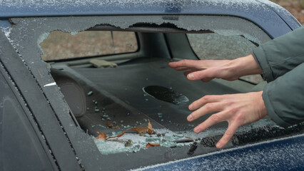 A thief's hands reach through a shattered car window on the street, capturing the moment of a theft. Broken glass reflects the urgency and danger of urban crime.