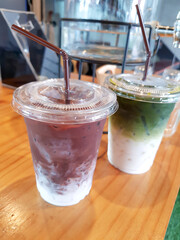 Green tea and cocoa mixed with cold milk in a plastic cup. A sweet chocolate drink in a cafe or...