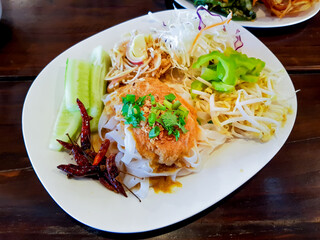Kanom Jeen Sen Chan Namya Kati, Top view of traditional Thai food. Noodles topped with curry paste and vegetables arranged on a white plate. Illustration concept for restaurant menu.