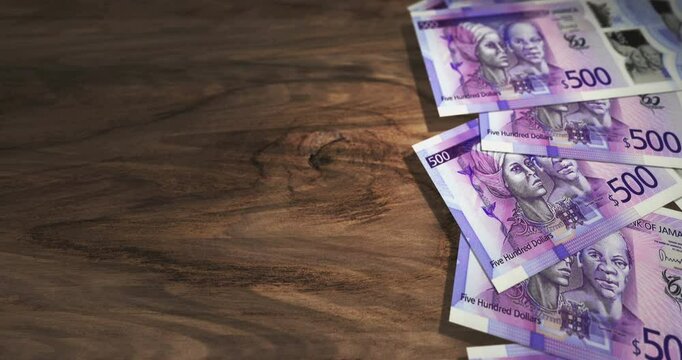 Jamaica dollar 500 JMD banknotes on the wooden table. Jamaican currency paper notes 3D concept background. Seamless and looped.