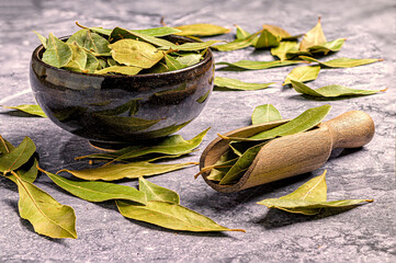 Dried bay leaves in a ceramic bowl on a stone surface