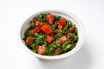 Tabbouleh Traditional Lebanese Salad made with Bulgur and Tomatoes and broken wheat, with cucumber, parsley, Mint, Oil and Lemon juice, seen up close and isolated on a white background