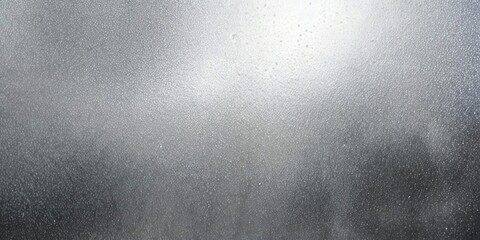 A fogged glass surface covered in condensation droplets. Light shines through the center, creating a diffused glow, with darker edges visible.
