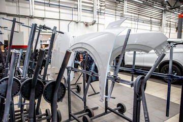 Several car fenders are drying after painting in a paint booth