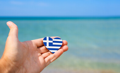 Flag of Greece in hand against the sea. Summer vacation in Greece