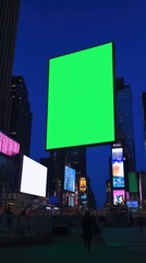A large green screen billboard in a city at night, surrounded by other illuminated billboards and buildings