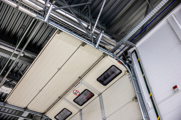 View of automatic sectional garage door from inside. hall gate in logistics warehouse from inside -...