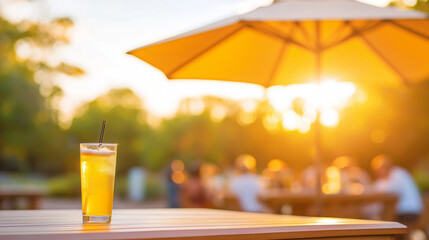Golden hour cocktail resting on weathered wooden surface, parasol overhead, friends socializing softly blurred in sunlit background