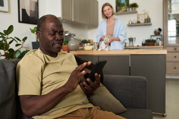 Elderly Man Using Tablet in Modern Cozy Living Room