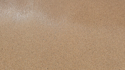 Little stones and sand in the summer day. Yellow sand on the beach near a sea.