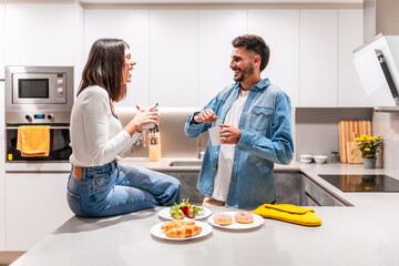 Happy couple enjoying breakfast and coffee in modern kitchen