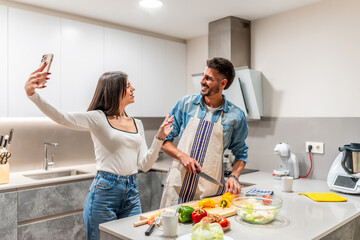 Couple making selfie while preparing vegetable salad in kitchen