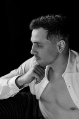 Young sexy handsome fit stylish man in a white shirt with naked torso looking at the camera in the studio. Close up portrait, casual clothes, modern style