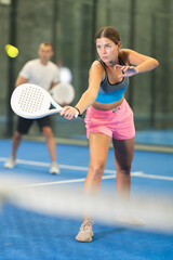 Young woman and young man playing doubles tennis on tennis court
