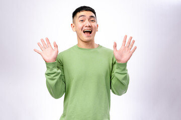 A cheerful Asian man in a green sweatshirt waves his hand with a bright smile. He stands against a...