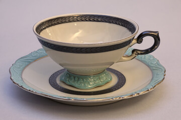 Still life with used vintage porcelain coffee cup or teacup and saucer. Close-up on light background with great depth of field.