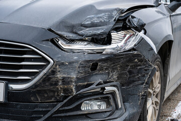 damaged front of black sedan after accident.