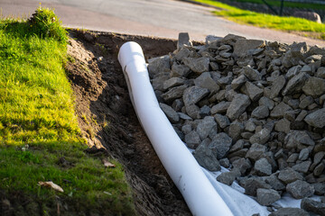 drainage pipe installation with gravel and soil in construction site.