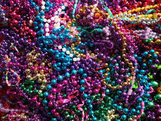 Mardi Gras beads assortment flat lay pile of multicolor parade throws New Orleans street festival necklaces