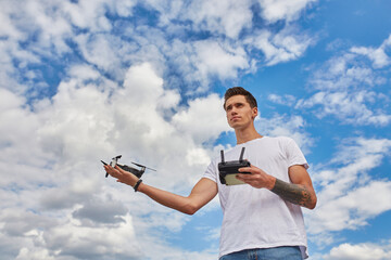 Man holding a drone under a blue sky