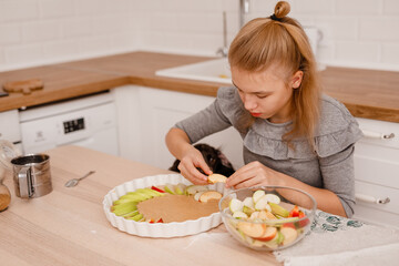 Teen girl baking in light kitchen with spaniel dog nearby asking for food