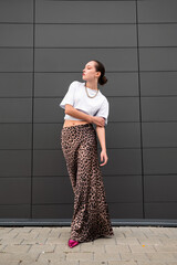 Confident Woman in Urban Fashion . Bold Leopard Print Skirt and White Crop Top