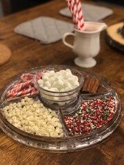 A cozy and festive arrangement featuring a hot chocolate station with marshmallows, candy canes, and sprinkles. Perfect for holiday or Christmas gatherings and creating a warm, inviting atmosphere.