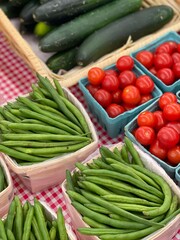 A vibrant display of fresh tomatoes, green beans, and cucumbers at a local farmers market, showcasing organic produce. Perfect for those seeking healthy and sustainable food options.