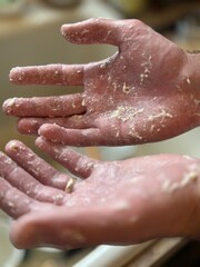 Fototapeta premium A detailed view of hands covered in dough, capturing the texture and messiness of baking. This image evokes rustic home cooking and culinary creativity in a kitchen environment.