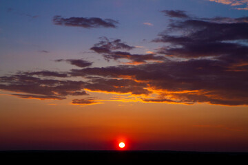 beautiful colored sky and thick clouds at sunset on field horizon