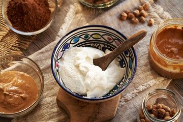 Greek yogurt in a bowl with nut butter, raw cacao and hazelnuts - ingredients for healthy sweets