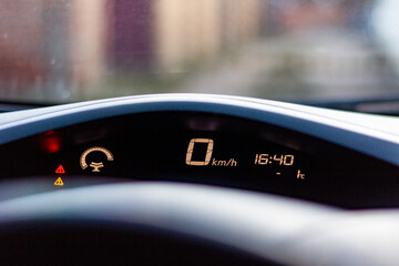 Car dashboard display shows zero speed and time at 16:40 in early evening light