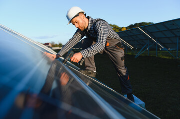 Worker installing solar panel on metal beams at sunny daytime. Renewable and ecological energy. Idea of environment safe. Modern technology and innovation. Man wearing workwear and helmet