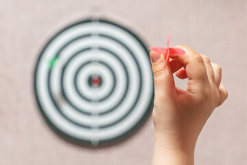 Playing darts, child's hand aiming a dart at a target