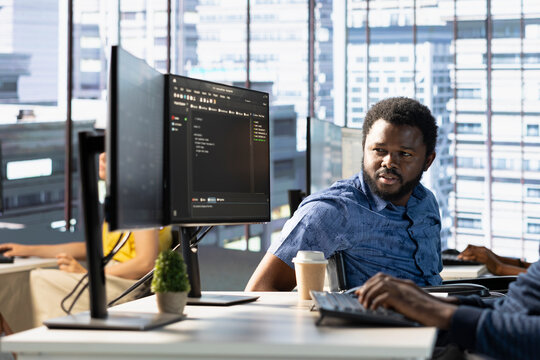 Manager in wheelchair supervising admin doing software quality assurance, reading source code on computer and implementing it. Team leader with disability checking on IT worker inspecting coding on PC - Powered by Adobe