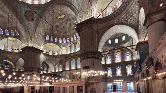 Intricately detailed Blue Mosque interior showcasing stunning architectural elements, vibrant stained glass windows, and ornate dome frescoes, Istanbul, Turkey
