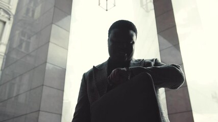 The striking silhouette of a man walking confidently through an urban archway is captivating