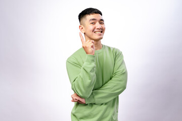 An Asian man in a green sweatshirt is smiling excitedly while raising one finger as if making a...