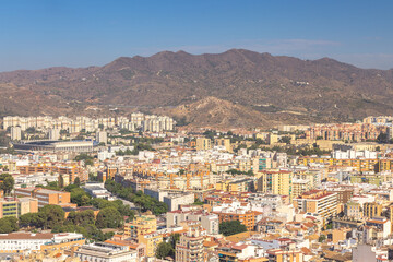 Malaga, seaside city in Andalusia, Spain, Europe. Panoramic city view with mountains in the background.  Residential buildings and a stadium are visible.
